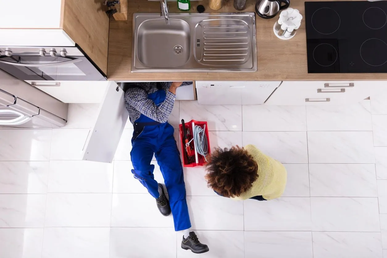 Plumber repairing a kitchen sink under the counter